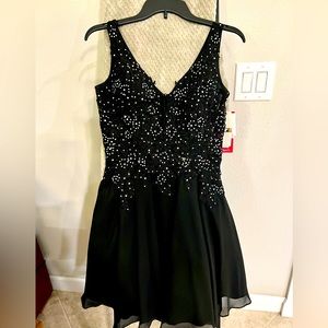 Black junior party dress with silver jewels. Fitted at top and flare at bottom.